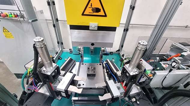 Zwei lineargeführte Greifer legen abwechselnd ein Bauteil in das Werkzeug der TOX®-Servopresse ein und entnehmen es nach dem Pressen.